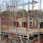 Mesh-sided scaffold loading bay platform with a lifting beam, cantilevered from a scaffold on a brick building
